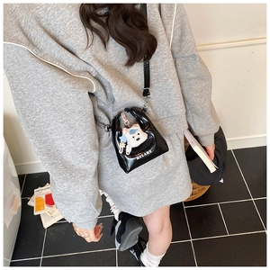 Gros plan du mini sac bandoulière en cuir verni noir avec un joli pendentif ours blanc
