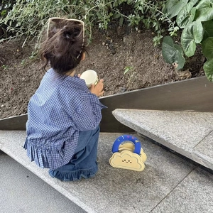 Detail of yellow cloud-shaped kids bag with blue handle and cute cartoon face