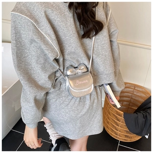 Détail du mini sac bandoulière argenté avec nœud, dentelle et logo Barbie