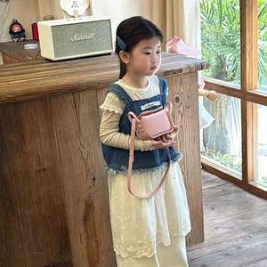 Pink mini crossbody bag in matte PU leather for girls shown on a child model outdoors