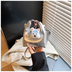 Détail du mini sac argenté avec lettrage HELAHE et pendentif en peluche chiot mignon