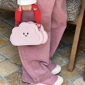 Close-up of pink cloud-shaped kids bag featuring an embroidered smiley face and red handle