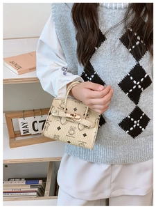 Close-up of cream children's handbag featuring bear print and metallic twist lock closure