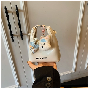 Gros plan du mini sac en cuir beige avec lettrage HELAHE et pendentif chien en peluche