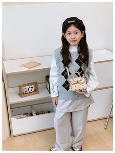 Detail view of beige kids handbag with cartoon bear prints and top handle on small model