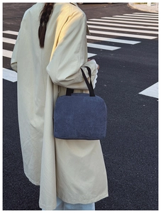 Blue corduroy tote bag shown in a street style view on a model wearing a beige coat