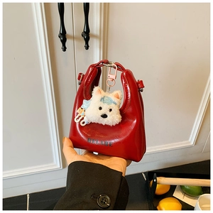 Gros plan du sac à main rouge brillant avec texte BELARE et pendentif chiot en peluche