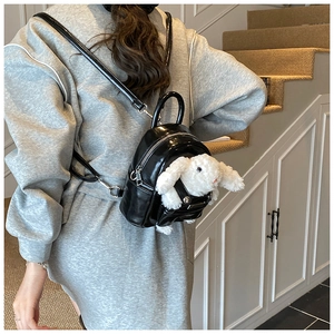 Vue détaillée du mini sac à dos noir brillant avec accessoire lapin en peluche blanc