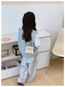 Detailed back view of a child wearing a beige cartoon bear print crossbody bag