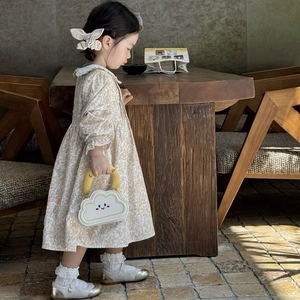 Toddler girl wearing floral dress and carrying a white cloud shaped mini handbag