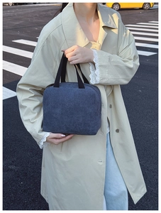 Detailed texture of gray corduroy tote bag with black canvas handles held by a model