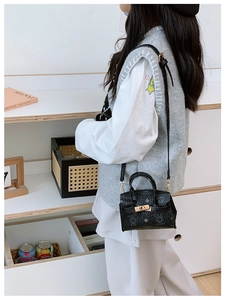 Detail view of cartoon bear pattern and metal swivel lock on a black kid shoulder bag