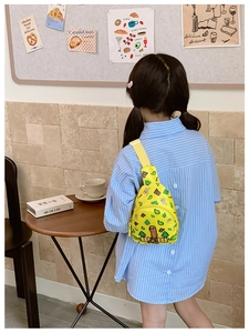 Détail d'un sac bandoulière jaune pour enfant porté par une fille dans un café