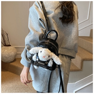Vue arrière d'un mannequin portant un mini sac à dos en cuir noir avec un lapin en peluche