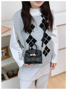 Detail of a black mini crossbody bag featuring cartoon bear print and gold hardware