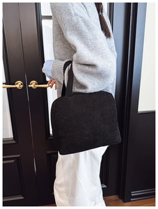Detail of a black corduroy handbag showing textured stripes in a fashion lifestyle setting