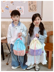 Détail de sacs à dos à cordon pour enfants aux couleurs contrastées et poches avant