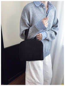Detail of high-density black corduroy handbag showing texture and sturdy handle
