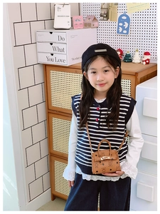 Close-up of brown cartoon bear mini crossbody bag with gold clasp on a child model
