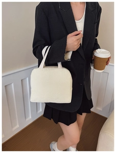 Close-up of cream corduroy tote bag held by a model in a minimal urban commuter setting