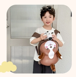 Detail of cute 3D cartoon dog hard shell backpack with plush ears on a young boy