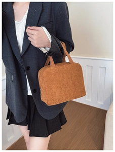 Brown corduroy handbag with vertical texture shown being carried by a model in casual attire