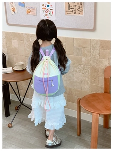 Vue arrière d'un enfant portant un sac à dos à cordon bicolore aux tons pastel doux