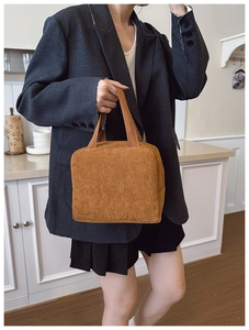 Detail of a brown corduroy tote bag held by a model in a minimalist kitchen setting