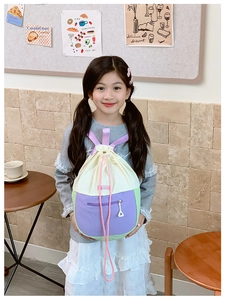 Détail d'un sac à dos enfant avec cordon de serrage, patchwork coloré et poche zippée