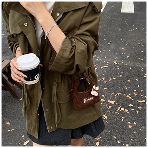 Detail of a dark brown plush mini crossbody bag with rabbit charm and Banma embroidery