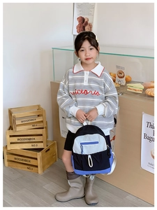 Detail view of large-capacity color-block school bag on a young girl model in a store