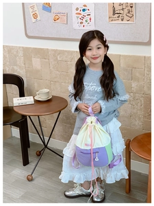 Détail d'un sac à dos enfant à cordon bicolore en crème, violet et vert pastel