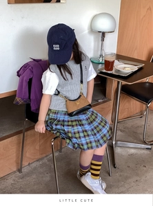 Mini quilted crossbody bag styled with a girl's knit vest and plaid skirt in a cozy cafe