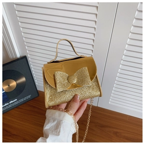 Close-up of golden sequin mini handbag featuring a large bow and metallic chain strap