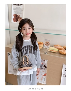Detail of leopard print shell bag for kids with gold chain strap in a warm cafe setting