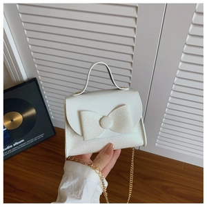 Close-up of white sequin bow handbag for girls with gold chain strap detail