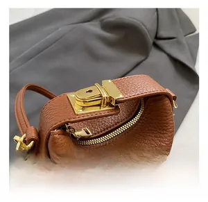 Close-up of brown pebbled leather handbag with gold metal lock and zipper detail