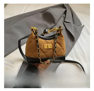Close-up of vintage brown suede quilted mini bag with golden metal chain and twist lock