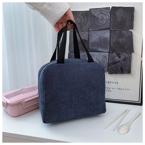 Detail view of a navy corduroy lunch bag featuring a striped texture and black handle