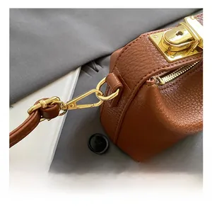 Detailed close-up of premium gold-tone metal hooks and hardware on brown leather bag