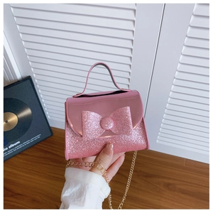 Close-up of pink sequin girls mini handbag with large bow and gold chain strap