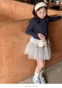 Mädchen-Outfit mit beigefarbener gesteppter Kettentasche und mehrlagigem Spitzenrock