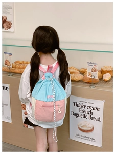 Détail de la fermeture à cordon et du design tricolore sur le sac à dos pour enfants
