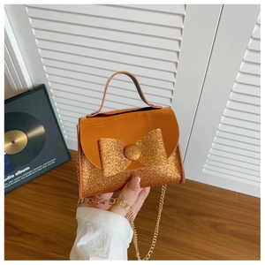 Detail of orange sequin bow handbag showing metallic gold chain and shiny texture