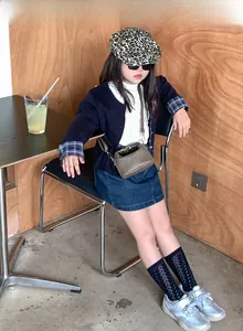Toddler fashion outfit featuring denim skirt and brown mini shoulder bag in casual style