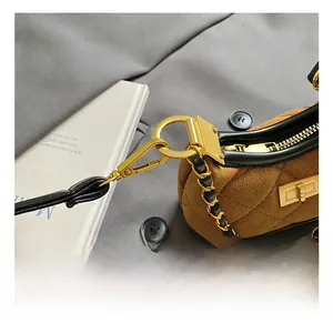 Close-up of caramel suede quilted bag with gold chain strap and metallic hardware details