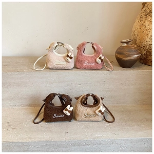 Close-up of mini plush bunny crossbody bags in cream white and pink on stone steps