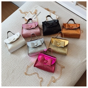 Flat lay of mini glitter handbags for girls with sequin bows and metal chain straps