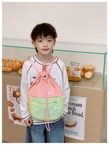 Sac à dos à cordon bicolore pour enfant en rose, jaune et vert dans une boulangerie lumineuse