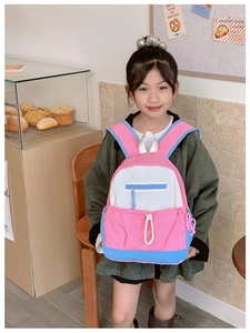 Detailed view of kids backpack featuring multi-pocket color block design on a child model